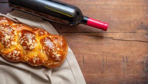 Challah bread with a bottle of red wine on wooden table, copy space